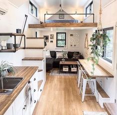 the interior of a tiny home with wood flooring and white walls, stairs leading up to an upper level loft