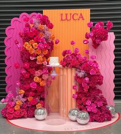 a pink and orange display with flowers on it's sides in front of a wall