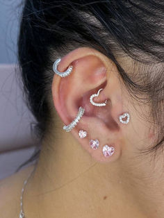 a woman with ear piercings on her ears and behind the ear is a pink heart