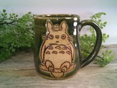 a ceramic mug with a totoro drawn on it