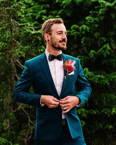 a man in a blue suit and bow tie is looking at the camera while wearing a boutonniere