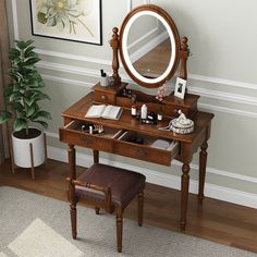 a dressing table with a mirror, stool and potted plant on the floor next to it