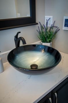 a black bowl sink sitting on top of a counter next to a vase with flowers