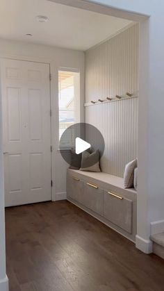 an empty entryway with a bench and coat rack on the wall next to it