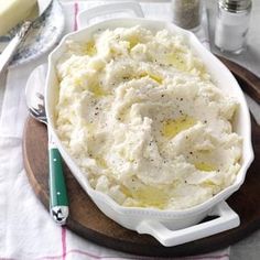 a bowl of mashed potatoes on a wooden plate