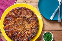 a yellow plate topped with a pastry next to a bowl of peas and a fork