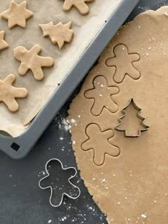 gingerbread cookies and cookie cutters on a baking sheet next to an uncooked cookie