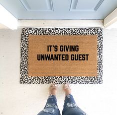 a person standing in front of a door mat that says it's giving unwanted guest