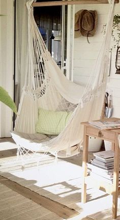 a white hammock sitting on top of a wooden floor next to a table