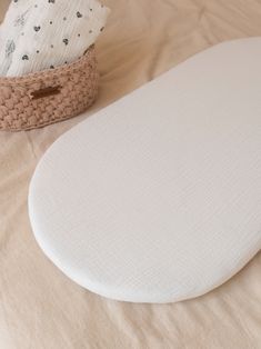 a close up of an oval shaped object on a bed with a basket in the background