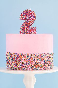 a birthday cake with sprinkles and a pink number one on the top