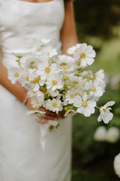 a bride holding a bouquet of white flowers