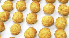 many small round pastries are lined up on a sheet of white paper, ready to be baked