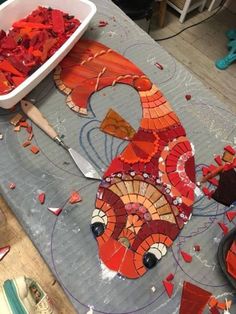 a table topped with lots of red and orange pieces of art