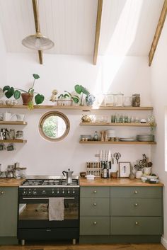 a kitchen with green cabinets and shelves filled with pots, pans and other items