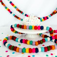 a white cake sitting on top of a plate covered in multi colored beads