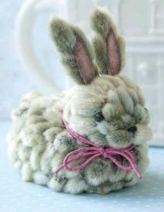 a small stuffed rabbit with a pink ribbon around its neck sitting on a blue table