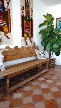 a wooden bench sitting next to a potted plant on top of a tiled floor