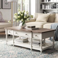 a living room with a couch, coffee table and flowers in a vase on top