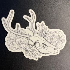 a sticker with flowers and a deer's head in the center on a black surface