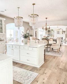 a large kitchen with white cabinets and chandeliers