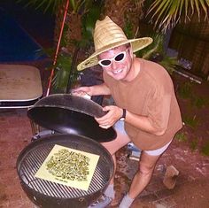 a man wearing a straw hat and sunglasses is cooking on an outdoor grill