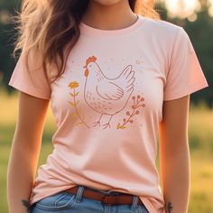 Embrace the charm of the countryside with our rustic chicken and flower shirt. Perfect for nature and animal lovers alike, this tee features a beautifully designed chicken amidst floral elements in a soft, inviting color palette. Made with high-quality materials, it offers both comfort and durability, making it a great addition to any wardrobe. Whether you're layering up for a brisk day or just showing off your love for farm animals, this T-shirt is sure to catch the eye and warm the heart. ☑️ P Country Style Tops With Graphic Print For Spring, Relaxed Fit Country Tops For Spring, Relaxed Fit Country Style Tops For Spring, Country Style Relaxed Fit Tops For Spring, Country Style Graphic Print Tops For Spring, Country Style Graphic Print T-shirt For Spring, Country Style Short Sleeve T-shirt For Spring, Spring Country Style T-shirt With Graphic Print, Western-themed Graphic Print Cotton Tops