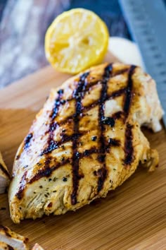 grilled chicken on a cutting board with lemon wedges