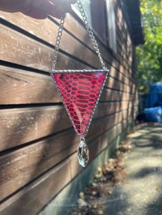 a red triangle shaped glass hanging from a chain