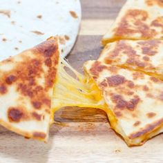 someone is cutting up some quesadillas on a wooden board