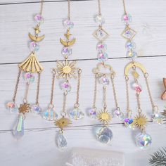 the sun and moon charms are hanging from chains on a white wooden table with pine cones