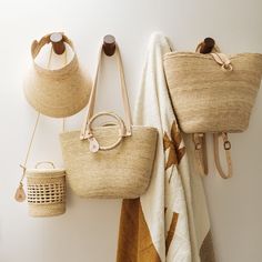 three purses hanging on the wall next to towels and other handbag items,