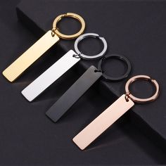 four different types of metal key chains on a black surface, one is gold, the other is silver