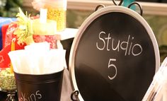 a blackboard sign sitting on top of a table next to some cups and candy