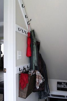 a coat rack with several coats hanging from it's hooks and two baskets on the wall