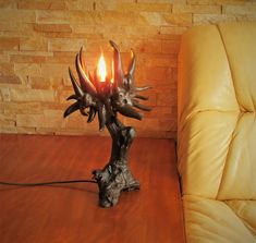 a table lamp sitting on top of a wooden table next to a yellow couch in front of a brick wall