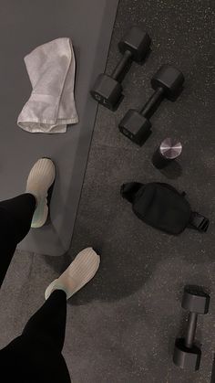 a person standing on the ground with their feet up next to some dumbbells