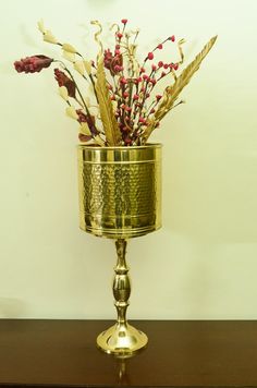 a gold vase filled with flowers on top of a wooden table