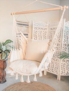 a white hanging chair next to a potted plant