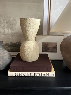 two vases sitting on top of books next to a lamp and other decor items