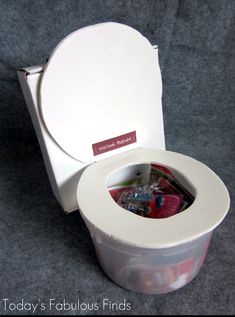 a white toilet with its lid open and some items in the container inside that is empty