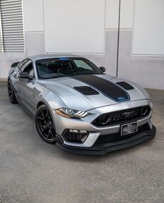 a silver ford mustang parked in front of a building