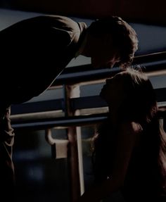 a man kissing a woman on the cheek while standing next to her in front of a railing