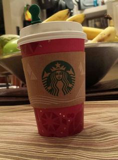 a starbucks cup sitting on top of a table next to some bananas and other fruit