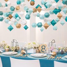 the table is set with blue and white plates, silverware and paper lanterns hanging from the ceiling