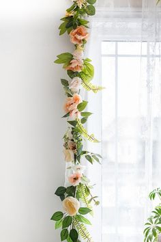 an arrangement of flowers and greenery on a window sill