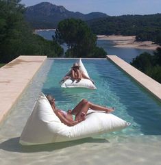 two women lounging on bean bags in an outdoor pool with mountains in the background