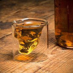 a glass filled with liquid sitting on top of a wooden table