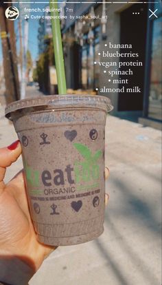 a person holding up a cup with a green straw in it and the words eat on