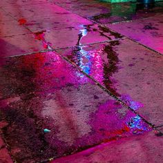 the sidewalk is wet and has puddles of water on it, as well as colorful lights